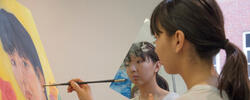 student painting a self portrait with a mirror