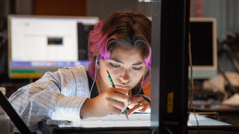 photo of a student drawing on a lit-desk