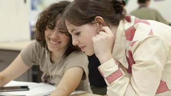 two students smiling at a desk