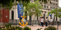 blue RISD flag on a street surrounded by buildings and trees