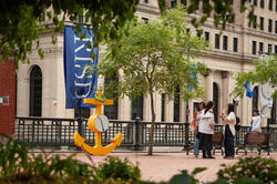 blue RISD flag on a street surrounded by buildings and trees