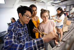 three students gathered around an easel