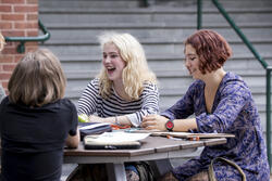 three students smiling at a table