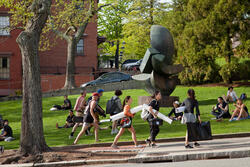 students walking up a hill holding large papers