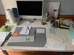 desk with computer, cutting mat, and art materials